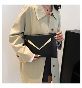 Macro detail of black chevron quilted envelope clutch with elegant gold V-metal logo