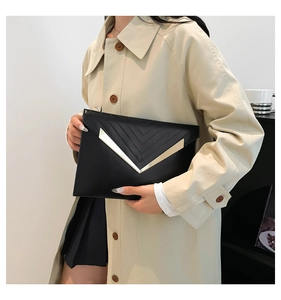 Detail of black envelope clutch with gold V-shaped buckle and elegant V-stitched texture