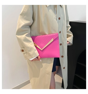 Detail of rose pink envelope clutch with gold V-shaped metal trim on minimalist handbag