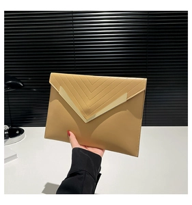 Close-up of beige envelope clutch with V-shaped gold metal trim held by a model