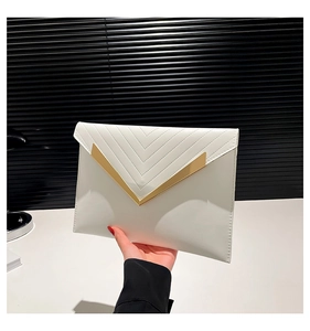 Detail of white envelope clutch with chevron quilting and golden V-shaped metal trim