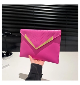 Macro view of rose red envelope clutch featuring V-shaped quilting and gold metal trim