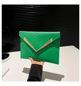 Detail of green envelope clutch showing V-shaped embroidery and gold metal trim
