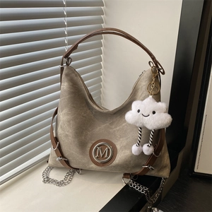 Retro khaki canvas hobo bag with brown leather trim and fluffy cloud charm on window sill