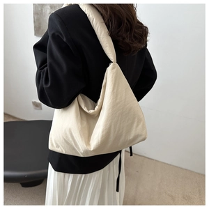 Dettaglio di una borsa tote imbottita color crema con tessuto trapuntato e spalline larghe