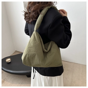 Détail du sac hobo en nylon vert armée avec texture matelassée porté avec une tenue chic