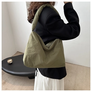 Dettaglio di una borsa tote oversize in nylon trapuntato verde oliva indossata da un modello