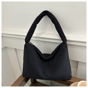 Vue détaillée d'un sac hobo noir rembourré avec bandoulière large sur une table en bois