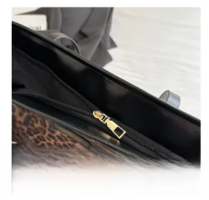 Detailaufnahme des glatten goldenen Metallreißverschlusses einer Tasche mit Leoprint