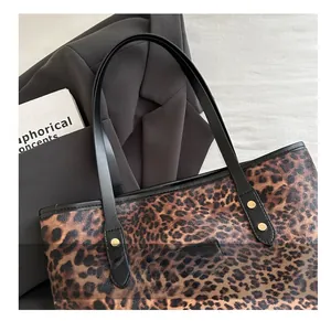 Close-up of leopard print tote bag featuring black leather straps and gold stud details