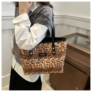 Detail of leopard print tote bag with black leather shoulder straps and metal rivets