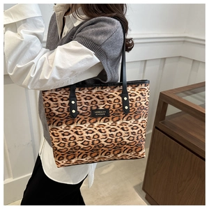 Detail of leopard print tote bag with black handles and golden rivet accents
