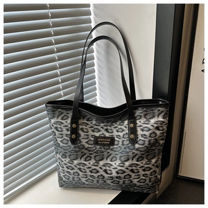 Detail der grau-schwarzen Totebag mit Leopardenmuster, Trägern und Markenetikett