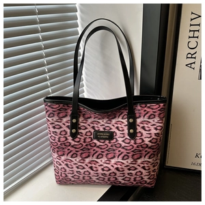 Detail der Leopard-Tasche mit Logo-Metallplatte und goldenen Nieten-Verzierungen