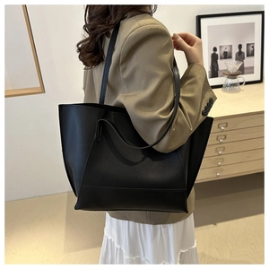 Close-up of a large black tote bag worn with a khaki blazer for a minimalist office look