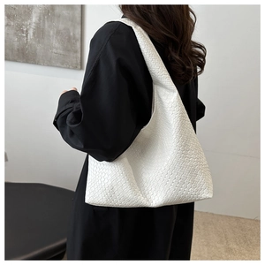 Detailed view of white woven textured hobo bag worn by a model as a shoulder tote