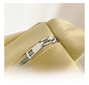 Detail showing smooth metal zipper and textured litchi pattern on cream crossbody bag