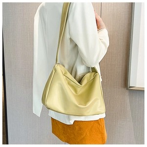 Pale green soft leather tote bag worn by a model in a minimalist indoor setting