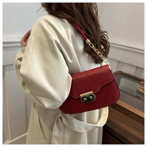 Close-up of red crocodile embossed crossbody bag with gold rectangular buckle and chain strap