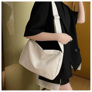 White minimalist crossbody bag with adjustable wide strap shown in a real-life commute use
