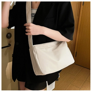Detail of off-white tote bag showing wide shoulder strap and smooth fabric texture