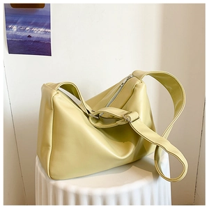 Detail of light yellow soft PU leather underarm bag with silver zipper on white stand