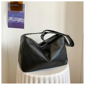 Close-up of minimalist black leather hobo bag with adjustable strap on white pedestal
