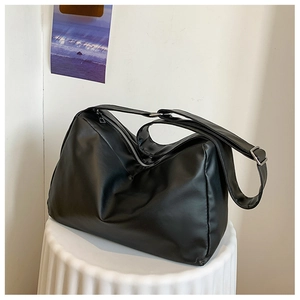 Detail of soft black PU leather tote with silver zipper and adjustable strap on a pedestal