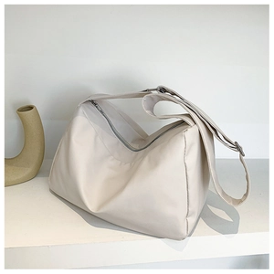 Detail view of adjustable strap and silver zipper on soft cream tote shoulder bag