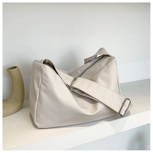 Detail of soft cream shoulder bag showing the zipper closure and adjustable wide strap