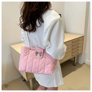 Close-up of pink quilted shoulder bag with silver bow detail and chain strap