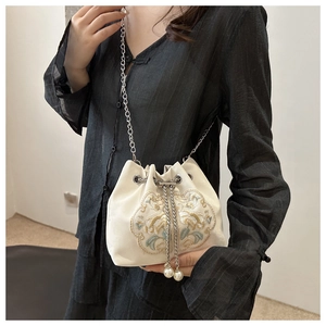 Detail of floral embroidery and pearl drawstring on a beige satin bucket bag