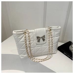 Detail of white quilted tote bag featuring silver bow buckle and gold chain strap