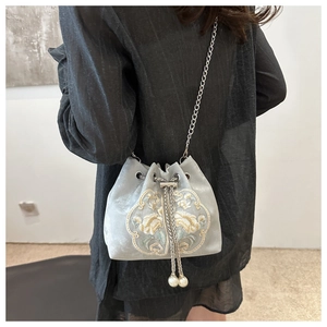 Close-up of light blue velvet bucket bag with floral embroidery and pearl drawstring