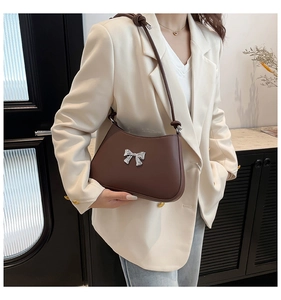 Détail du sac sous le bras marron foncé avec noeud en métal argenté sur cuir synthétique