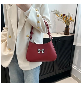 Détail d'un sac bandoulière bordeaux avec nœud argenté et lanière à nœud décoratif