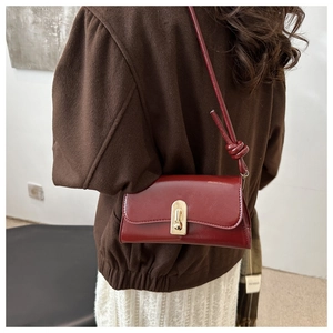 Detail of vintage burgundy leather shoulder bag with gold metal lock and knot strap