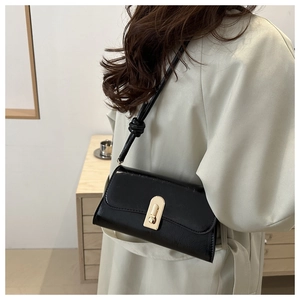 Minimalist black leather crossbody bag featuring gold hardware and knotted shoulder strap