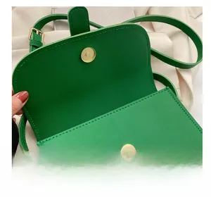 Detail of green leather crossbody bag showing magnetic snap closure and fine stitching