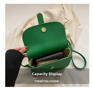 Interior detail of green crossbody bag showing space for phone and wallet with metal clasp