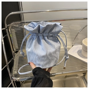 Detail of light blue drawstring bucket bag with unique water ripple pleated texture