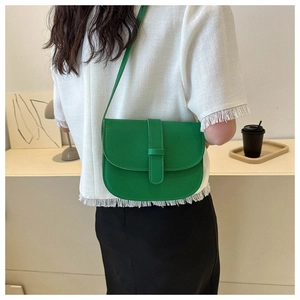 Detail of vibrant green leather saddle bag with buckle and fine stitching on a model