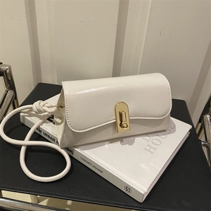 Chic beige crossbody square bag with gold oval clasp on a luxury aesthetic book