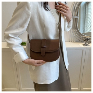 Dark brown saddle bag with smooth matte leather on a model in a white blazer
