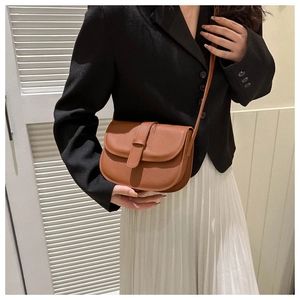 Close-up of a vintage brown crossbody bag with matte leather texture on a female model