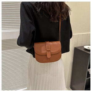 Rear view of a brown vintage saddle crossbody bag shown on a model for scale and fit