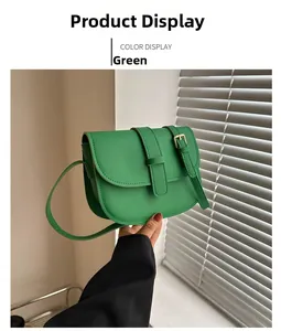 Detail shot of a green matte crossbody bag with a round bottom and adjustable gold buckle strap