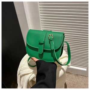 Close-up of emerald green leather saddle bag with gold metal buckle and sleek strap
