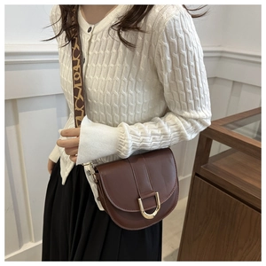 Brown saddle bag with golden horseshoe buckle and patterned wide shoulder strap