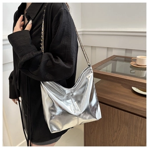 Detail of silver metallic tote bag featuring mirror finish and gold chain shoulder strap